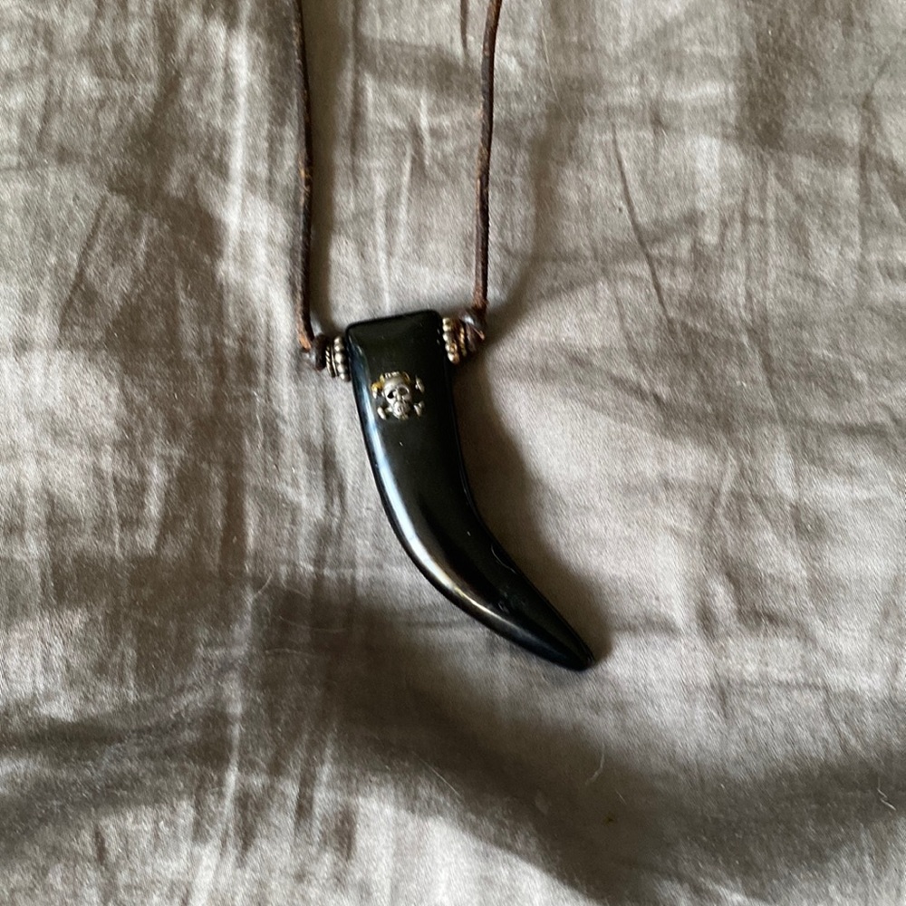 On leather , a black horn with silver skull on it